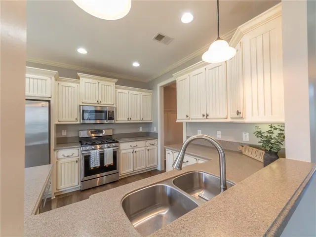 a kitchen with stainless steel appliances a sink a stove a microwave a center island and cabinets