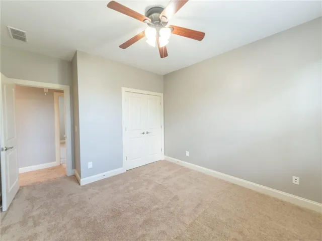 an empty room with closet and a chandelier fan