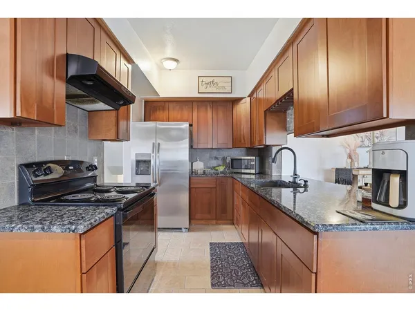 a kitchen with granite countertop a sink a stove and a wooden cabinets