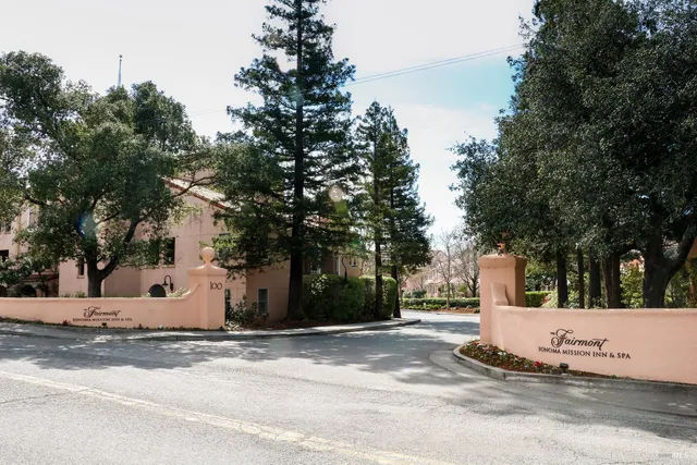 a view of a white house with a road and a trees