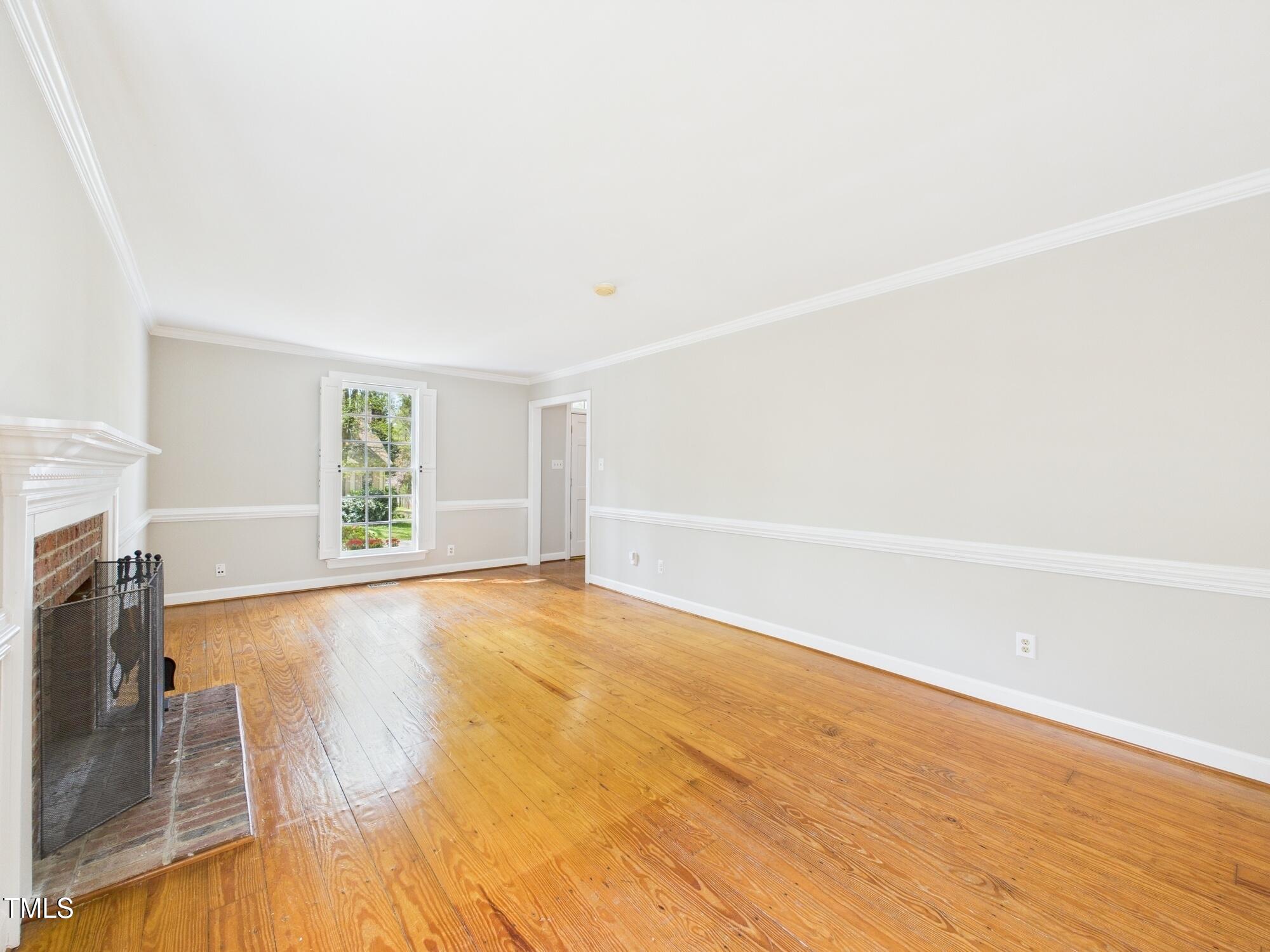 7117 Sandringham Drive Raleigh, NC 27613 - Photo 14 of 54 a view of an empty room with a fireplace and a window