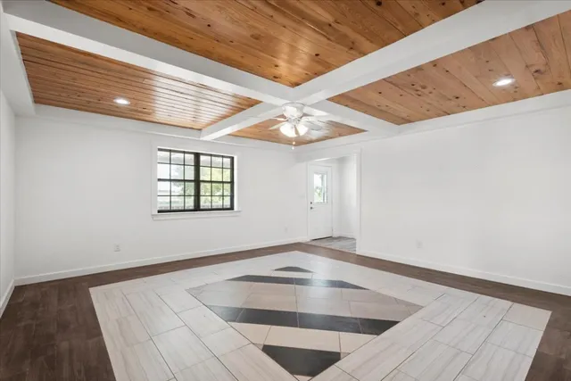 a view of an empty room with window and wooden floor