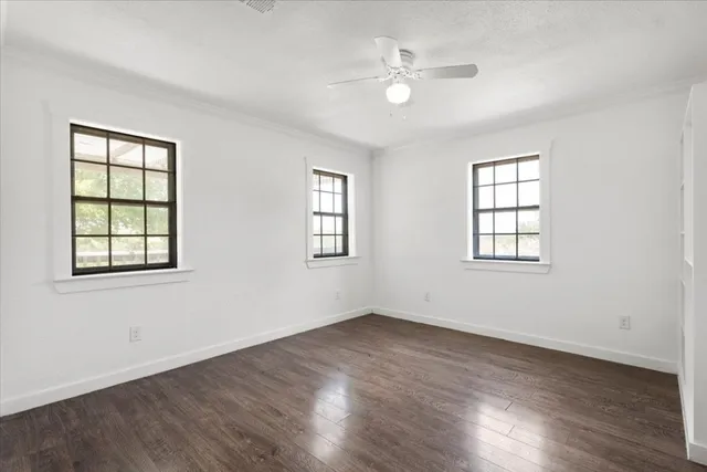 a view of an empty room with a ceiling fan window and a ceiling fan