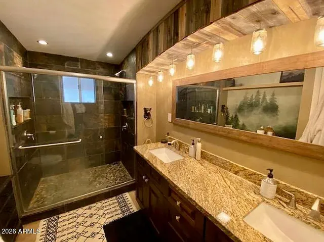 a bathroom with a granite countertop sink a mirror and shower