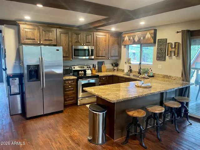 a kitchen with granite countertop a table chairs microwave and refrigerator