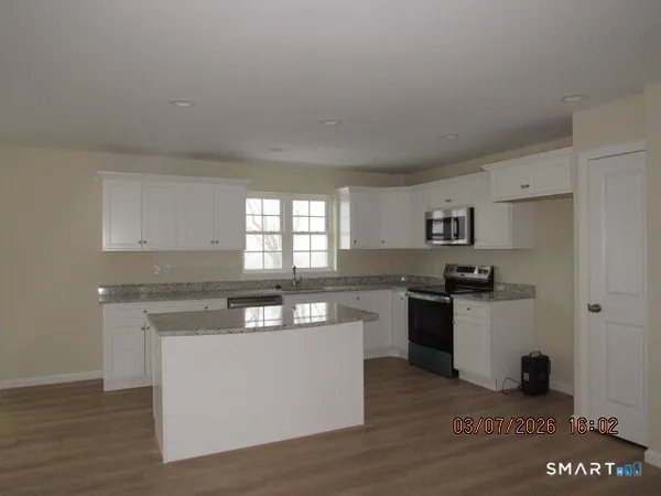 a kitchen with stainless steel appliances granite countertop a stove a sink dishwasher and a refrigerator with wooden floor