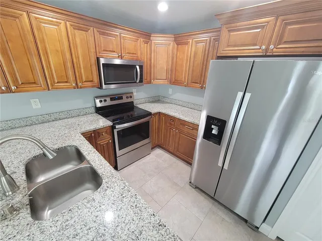 a kitchen with granite countertop a refrigerator stove and microwave