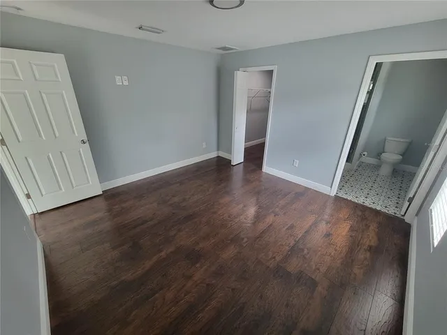 an empty room with wooden floor and entrance