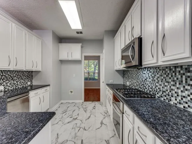 a kitchen with granite countertop a sink stove and cabinets