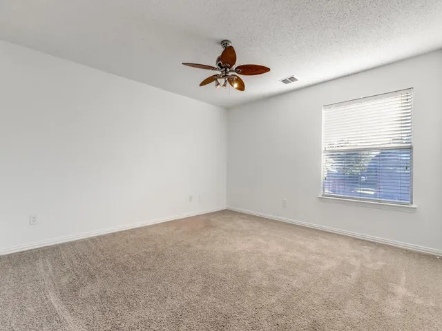 an empty room with windows and fan