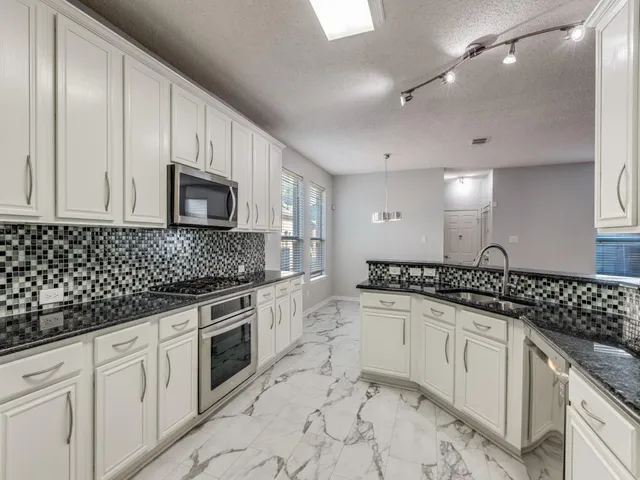 a kitchen with granite countertop a sink a stove and cabinets