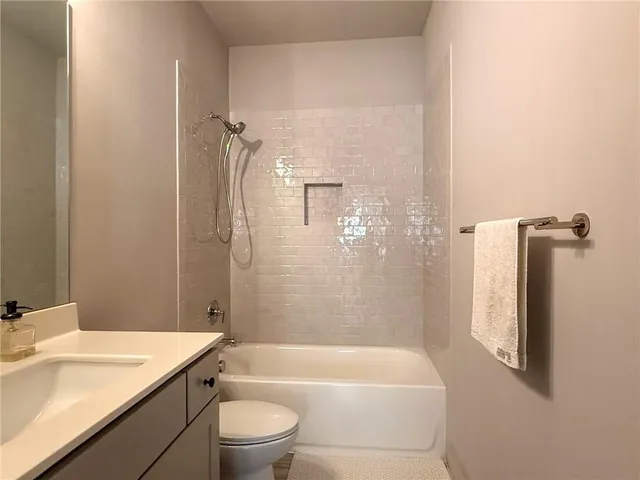 a bathroom with a granite countertop bathtub shower sink vanity and toilet