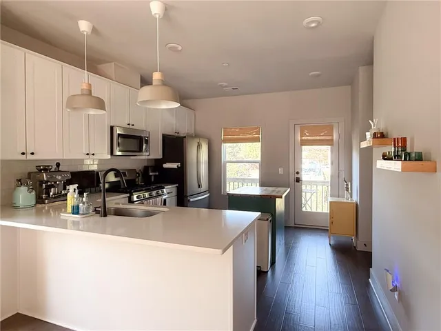 a kitchen with sink a refrigerator and white cabinets