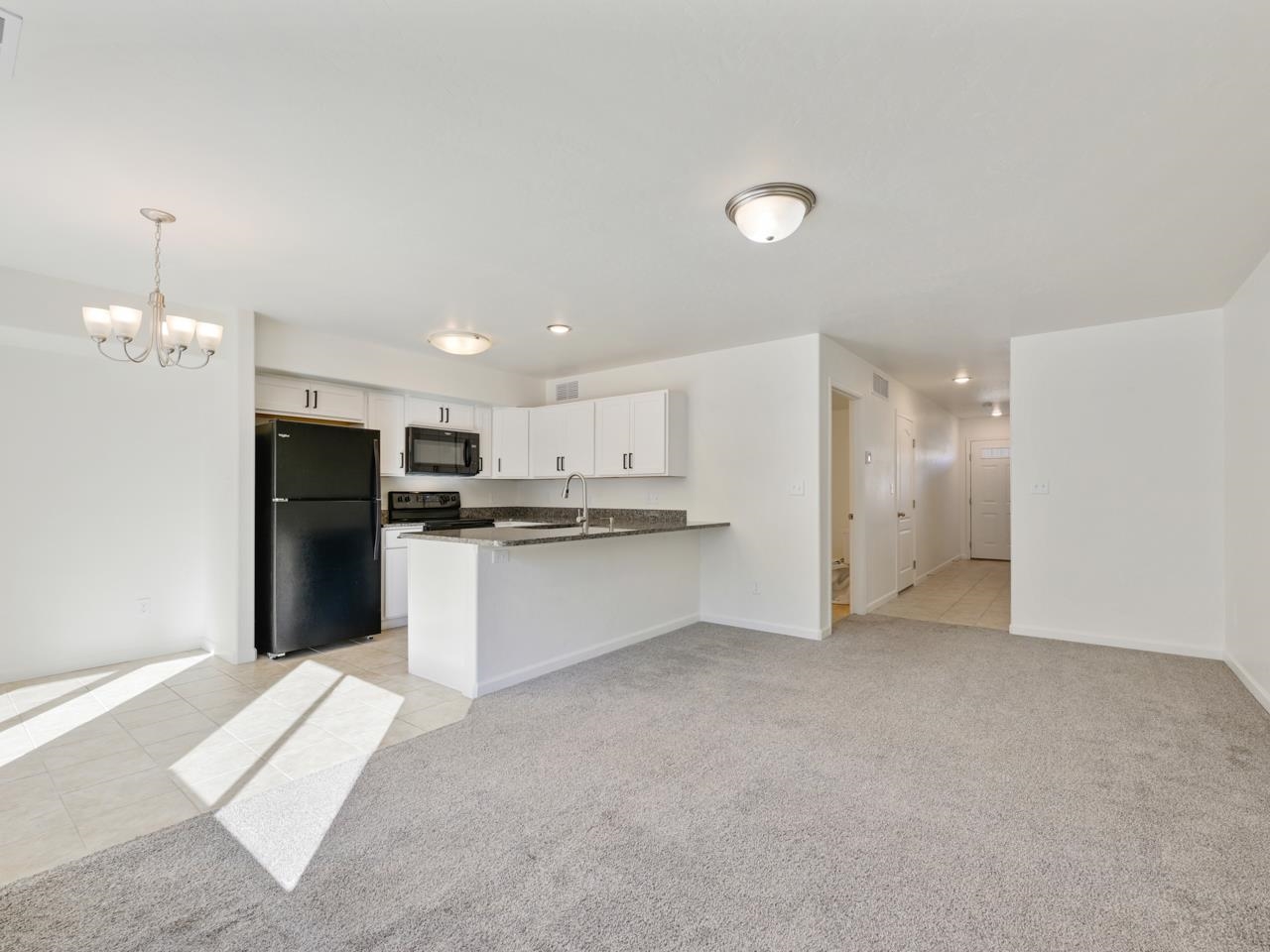 655 Trinity Way, Unit C Grand Junction, CO 81505 - Photo 4 of 20 a view of a kitchen with refrigerator and white cabinets