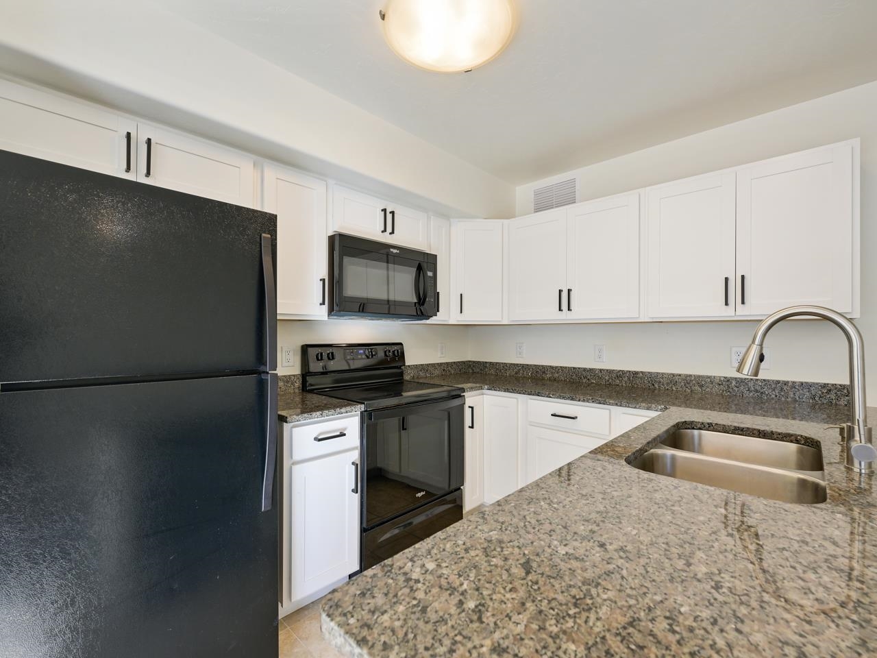 655 Trinity Way, Unit C Grand Junction, CO 81505 - Photo 6 of 20 a kitchen with stainless steel appliances granite countertop a refrigerator a stove a sink a microwave and white cabinets