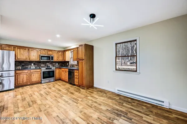 a large kitchen with kitchen island a stove a refrigerator cabinets and a dining table
