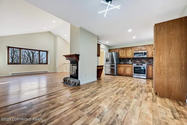a kitchen with stainless steel appliances granite countertop a refrigerator a stove top oven a sink dishwasher and white cabinets with wooden floor