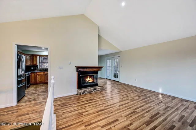 a view of an empty room with wooden floor and windows