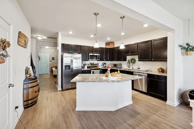 a view of kitchen with stainless steel appliances wooden floor and refrigerator