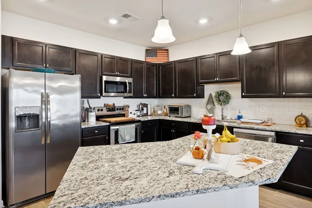 a kitchen with stainless steel appliances granite countertop a sink refrigerator and microwave