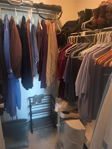 a view of walk in closet with clothes and shoes