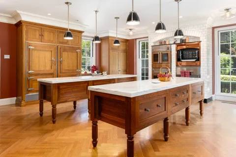 a room with stainless steel appliances kitchen island granite countertop a refrigerator a stove and a dining table with wooden floor