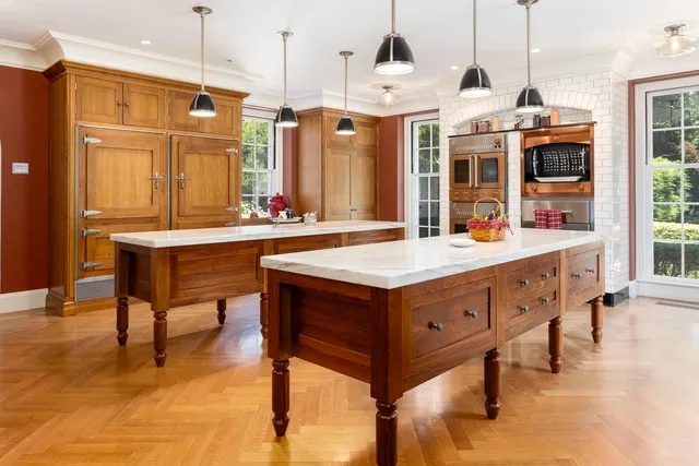 a room with stainless steel appliances kitchen island granite countertop a refrigerator a stove and a dining table with wooden floor