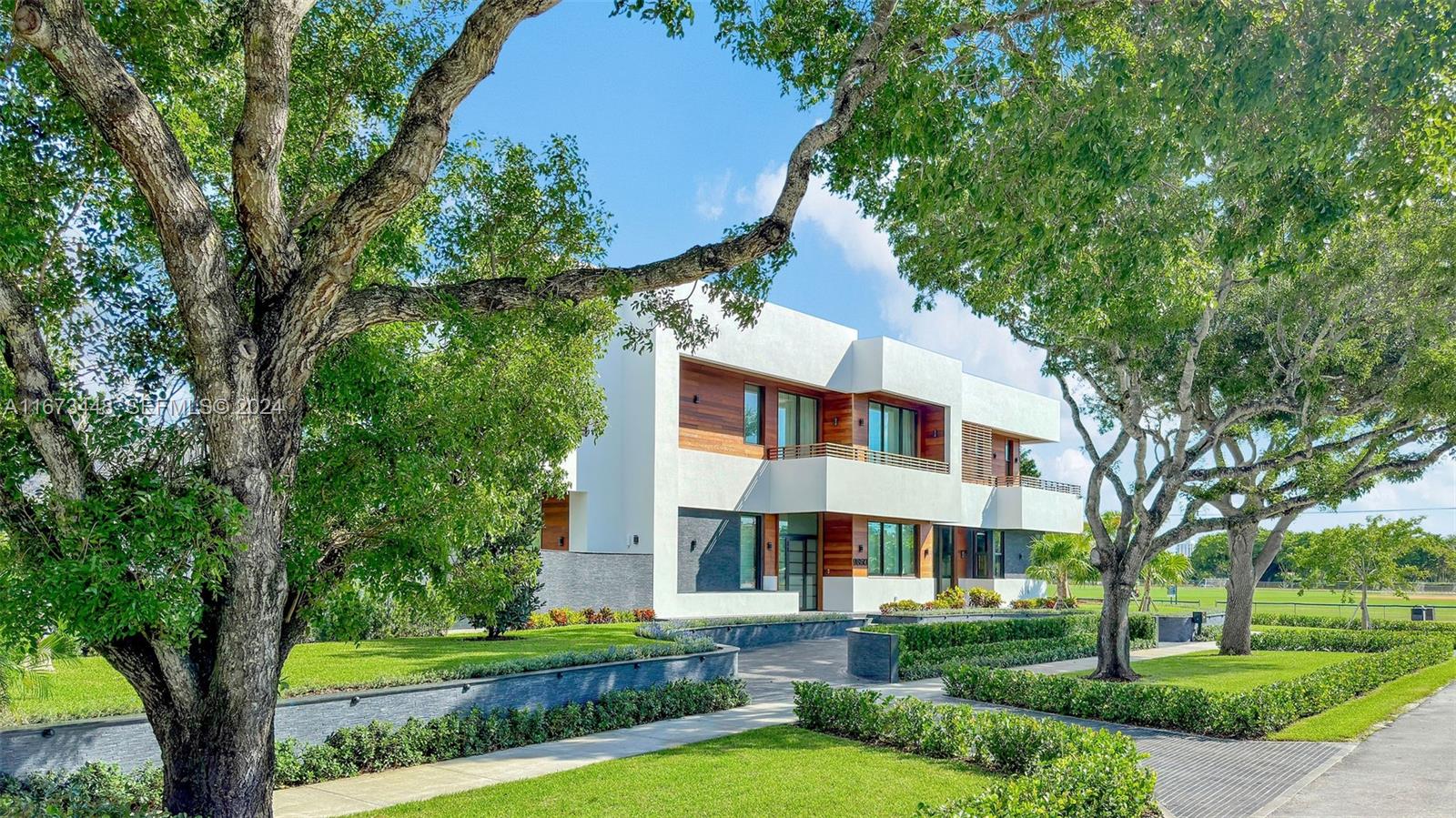 9860 Northeast 5th Avenue Road Miami Shores, FL 33138 - Photo 2 of 56 a view of a white house next to a yard with big trees