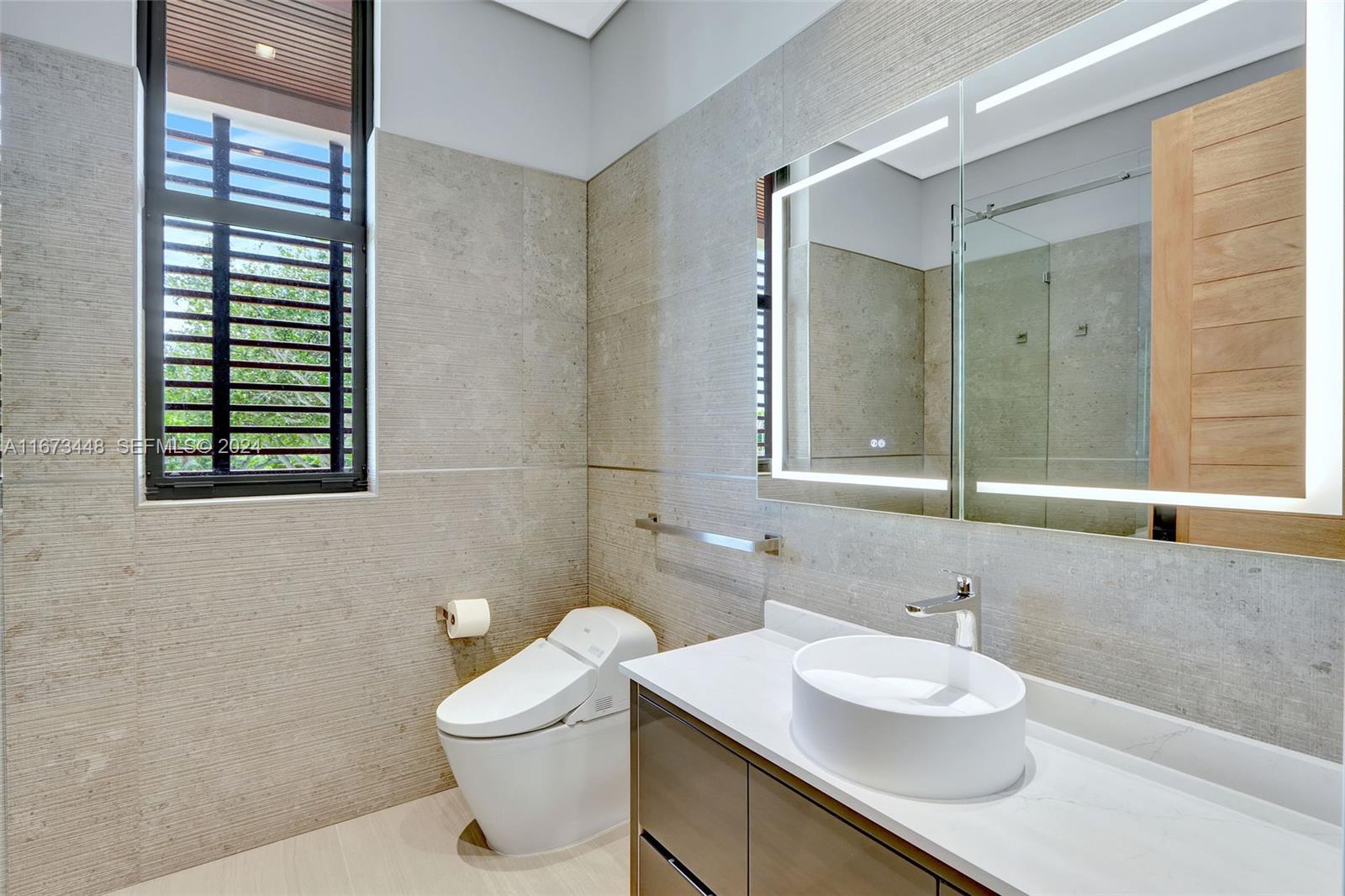 9860 Northeast 5th Avenue Road Miami Shores, FL 33138 - Photo 43 of 56 a bathroom with a toilet sink and mirror