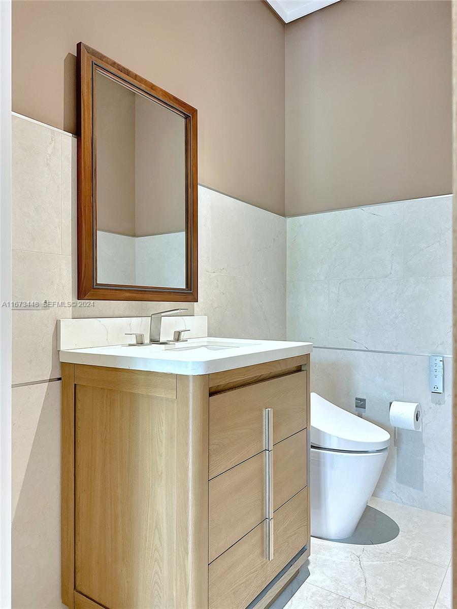 9860 Northeast 5th Avenue Road Miami Shores, FL 33138 - Photo 54 of 56 a bathroom with a granite countertop sink a toilet and a mirror