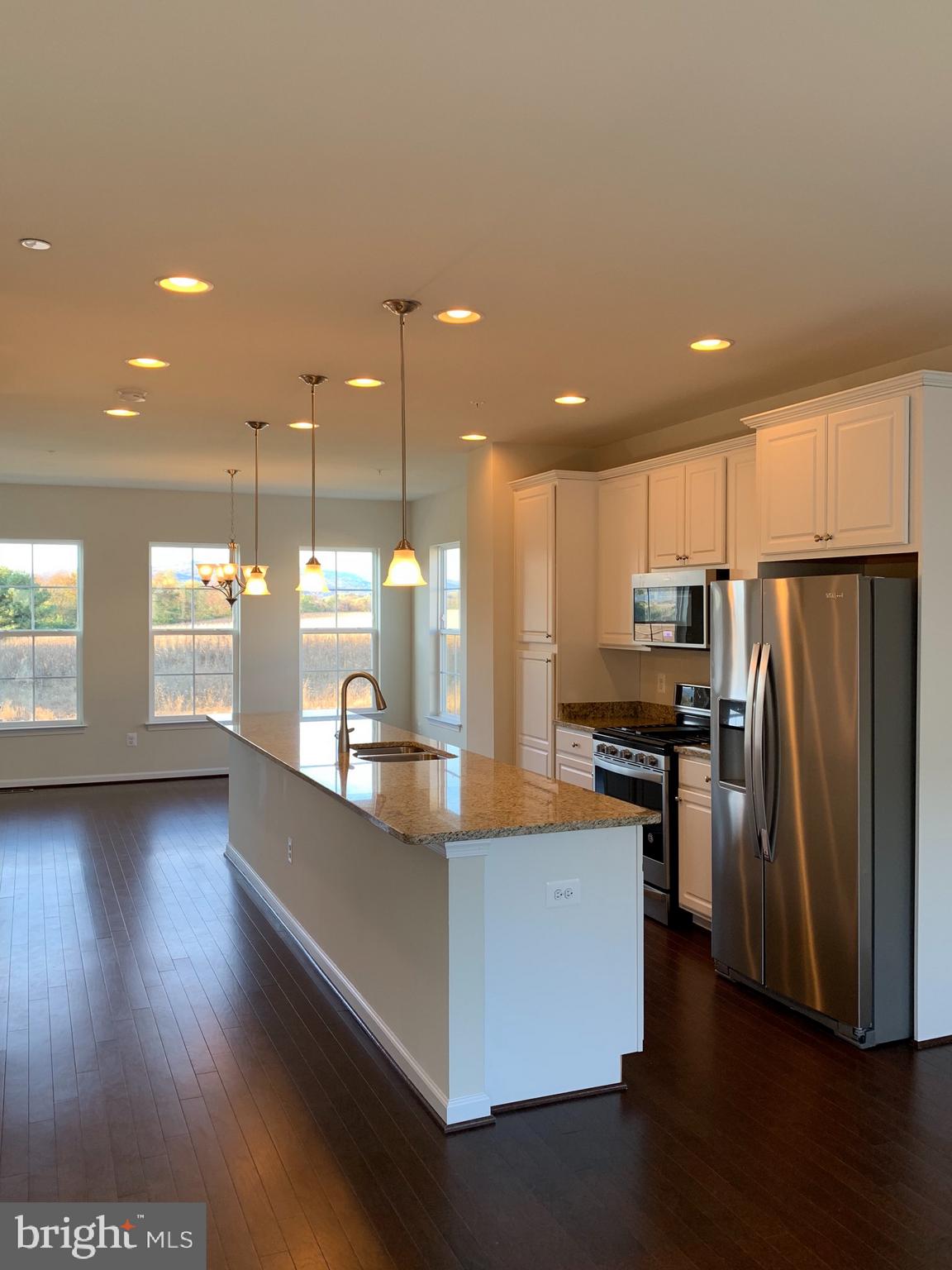 6113 Jefferson Pike Frederick, MD 21703 - Photo 3 of 12 a kitchen with stainless steel appliances kitchen island granite countertop a refrigerator a stove and a wooden floors