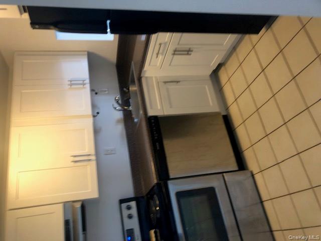 2 Richmond Road, Unit 6F Lido Beach, NY 11561 - Photo 5 of 14 Kitchen featuring dark countertops, range, white cabinetry, light tile patterned flooring, and dishwasher
