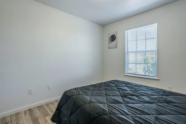 a view of a bedroom with wooden floor and window