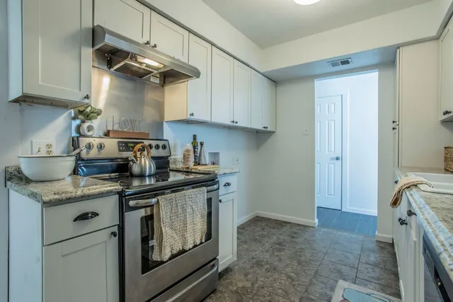 a kitchen with stainless steel appliances granite countertop a sink a stove and a refrigerator