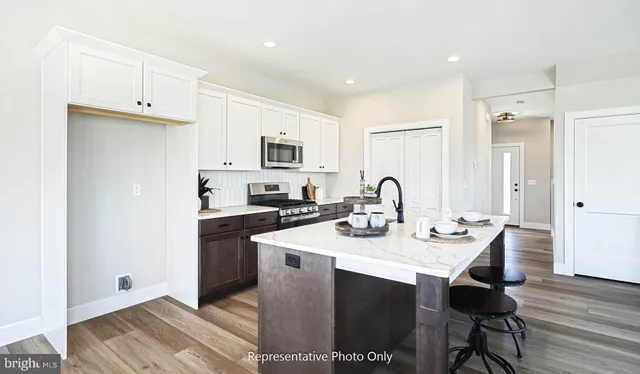 a kitchen with granite countertop a stove a microwave a sink and white cabinets