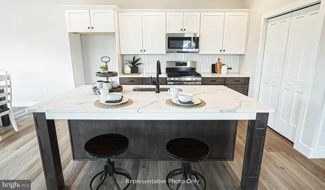 a kitchen with stainless steel appliances granite countertop a stove a sink a refrigerator and white cabinets with wooden floor