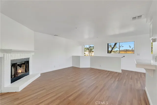 a view of empty room with wooden floor and fireplace