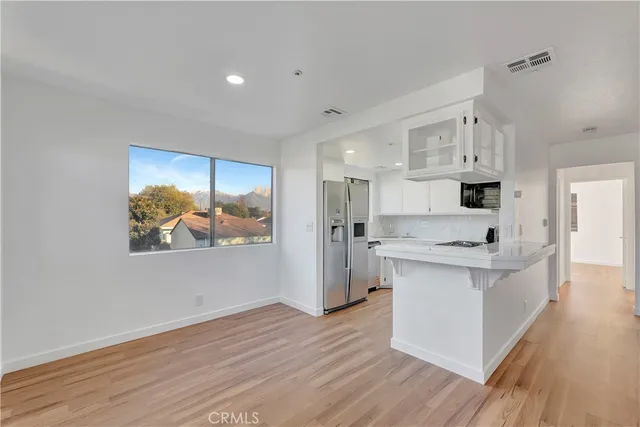 a open kitchen with white cabinets and wooden floor