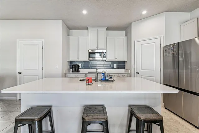 a kitchen with stainless steel appliances a sink a stove a refrigerator cabinets and a table