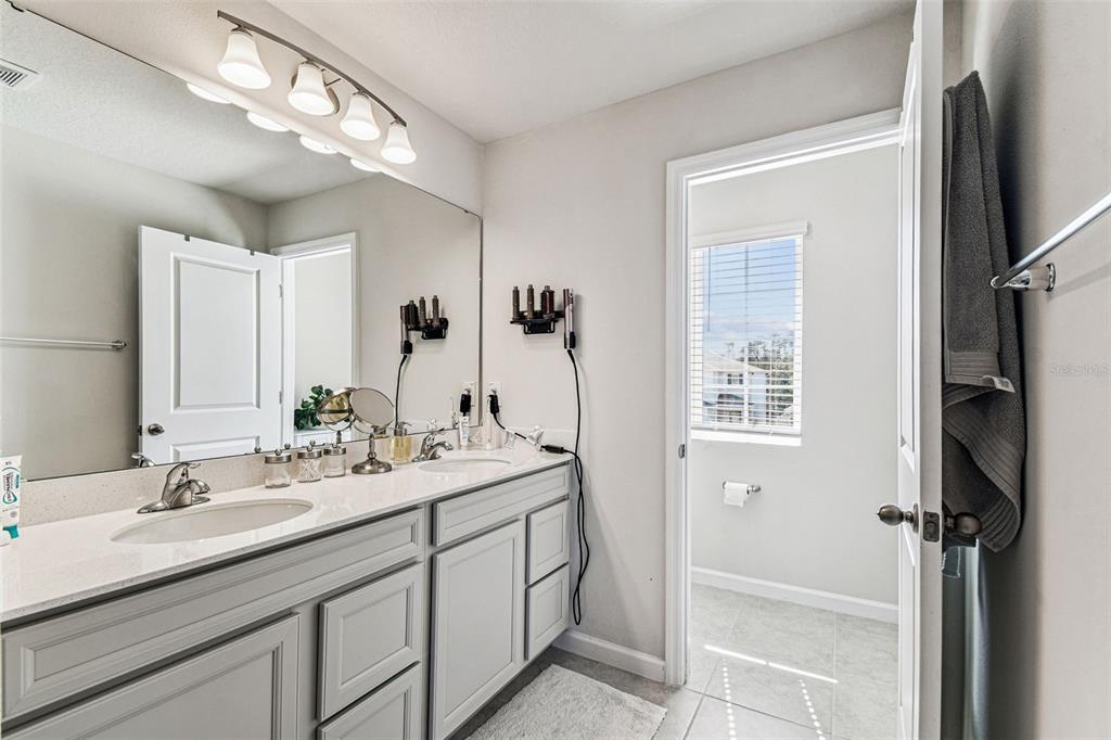 19043 Pebble Wood Ln Spring Hill Spring Hill, FL 34610 - Photo 22 of 35 a bathroom with a double vanity sink a mirror and a shower