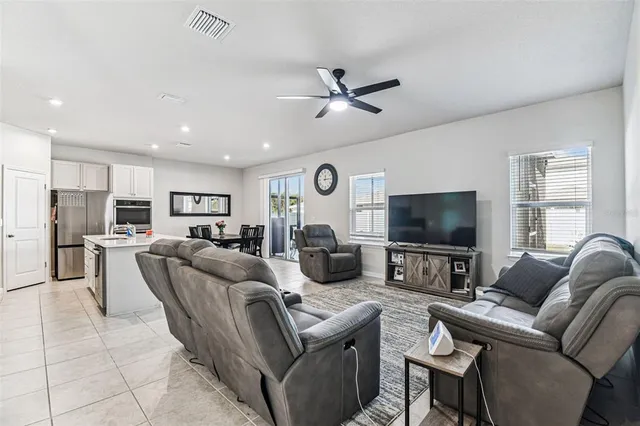 a living room with furniture a ceiling fan and a flat screen tv
