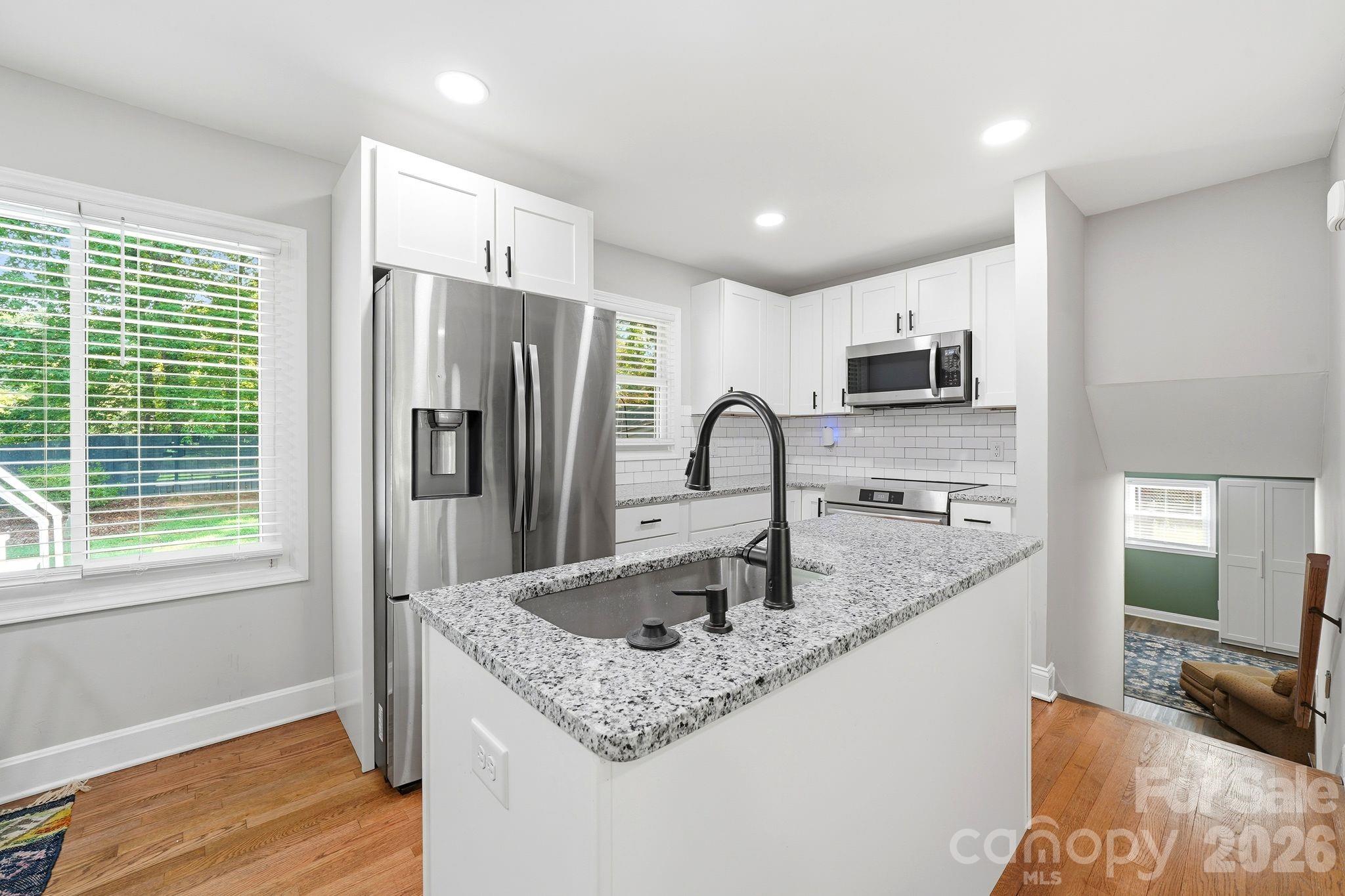 7552 Idlewild Road Charlotte, NC 28212 - Photo 32 of 40 a kitchen with stainless steel appliances granite countertop a sink stove and refrigerator