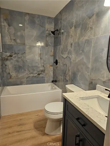 a bathroom with a granite countertop bathtub sink vanity mirror and toilet
