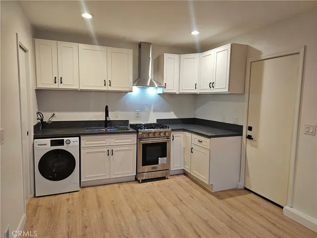 a kitchen with granite countertop a stove a sink and a refrigerator