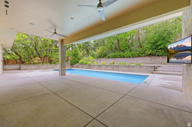 1389 Millbrook Way Bountiful, UT 84010 - Photo 60 of 74 Expansive covered patio featuring a rectangular swimming pool, concrete hardscaping, stone veneer columns, and dual ceiling fans
