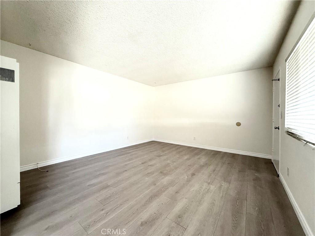 489 West Alpine Street, Unit F Upland, CA 91786 - Photo 2 of 12 an empty room with wooden floor and windows