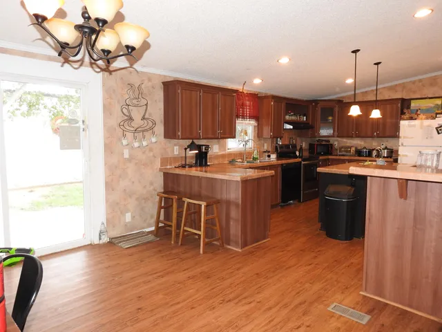 a kitchen with stainless steel appliances granite countertop a sink a stove and a wooden floors