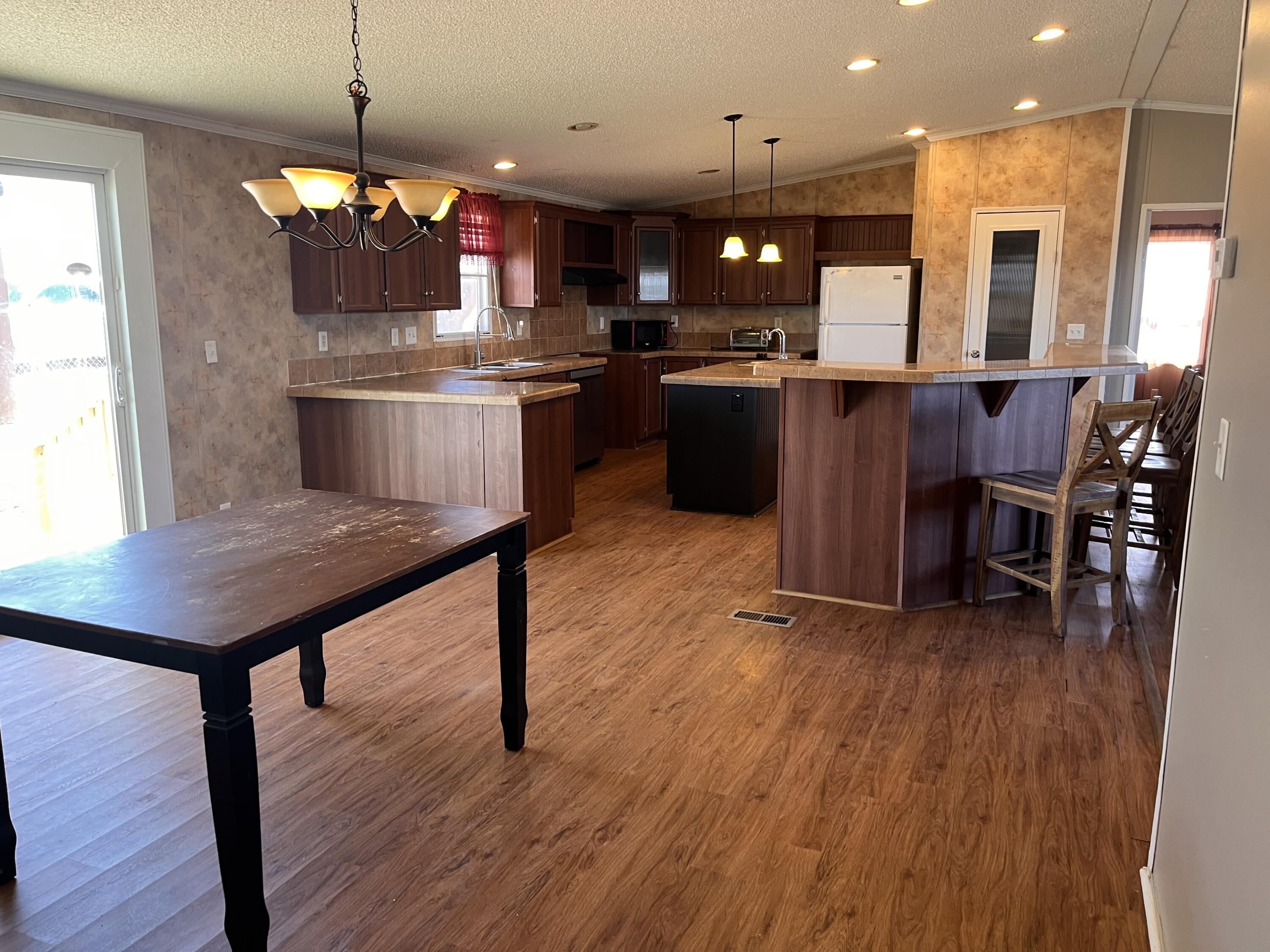 35 Rangeview Road Spur, TX 79370 - Photo 10 of 36 a kitchen with stainless steel appliances kitchen island granite countertop a stove a refrigerator a kitchen island a sink and a dining table with wooden floor