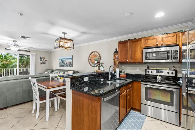 a kitchen with stainless steel appliances granite countertop a stove top oven a sink dishwasher a dining table and chairs with wooden floor