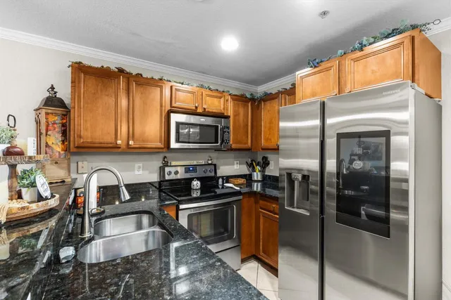 a kitchen with granite countertop a refrigerator stove and sink